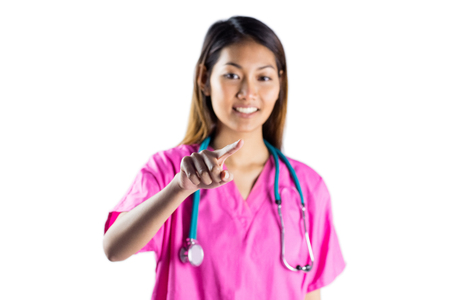 Asian nurse with stethoscope pointing in front of her on white screenの写真素材