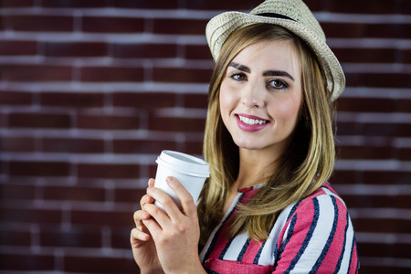 Woman drinking a beverage and wearing a hatの写真素材