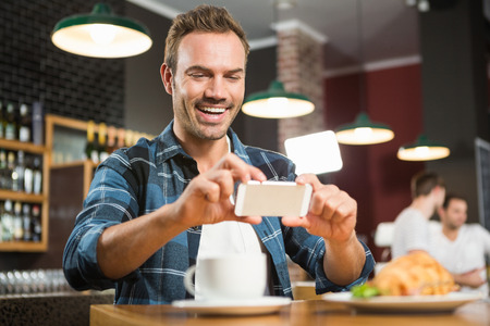 Handsome man taking a picture of his sandwich in a pubの写真素材