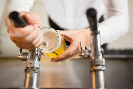 Masculine hands pouring a pint in a pubの写真素材