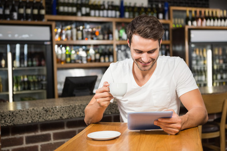 Handsome man using tablet and having coffee in a pubの写真素材