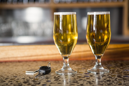 View of two pints of beer and car keys on a counter in a barの写真素材
