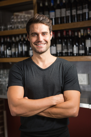 Handsome bar tender standing behind his counter in a pubの写真素材