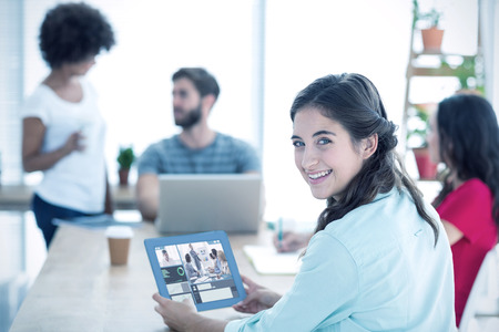 Smiling businesswoman using tablet  against business people in conference meetingの写真素材