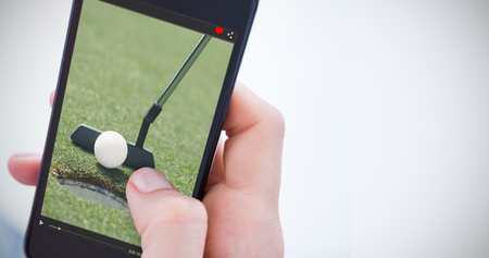 Woman using her mobile phone against golf club putting ball at the holeの写真素材
