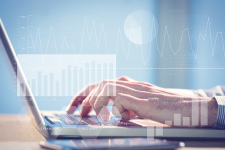 Business interface with graphs and data against businessman using laptop at desk