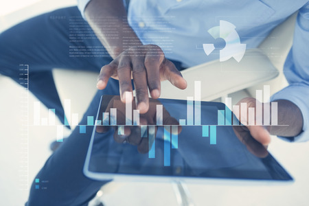 Business interface with graphs and data against businessman using digital tablet while sitting on...