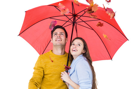 Happy couple under an umbrella throwing leaves on white backgroundの写真素材