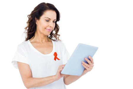 Woman with red aids awareness ribbon using tablet on white background
