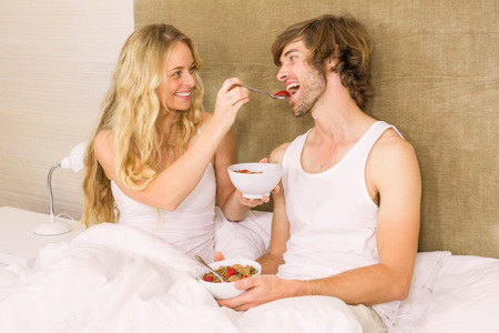 Cute couple having breakfast in bed in the bedroomの写真素材