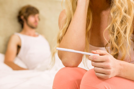 Worried woman waiting the pregnancy test result with boyfriend on backgroundの写真素材