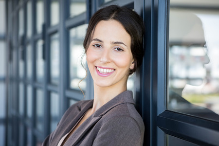 Portrait of young businesswoman leaning on office door