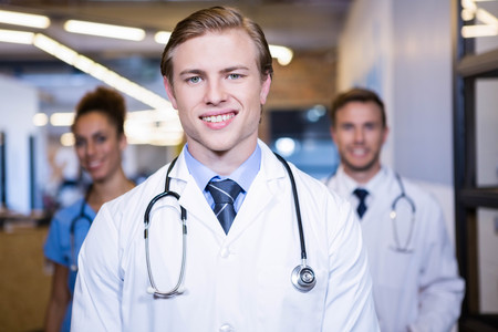 Portrait of doctor smiling in hospital and colleagues standing behindの写真素材