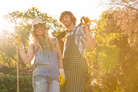 Smiling couple in the garden holding a rake and a shovelの写真素材