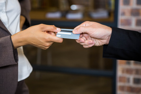 Businessman and businesswoman holding a credit card in officeの写真素材