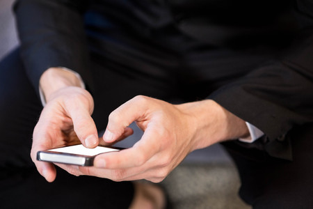 Close-up of businessman text messaging on smartphoneの写真素材
