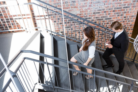 Businessman and businesswoman climbing staircase in office