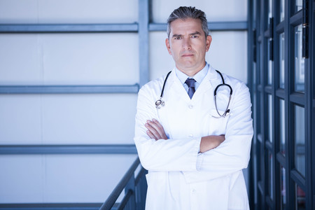 Portrait of serious male doctor standing with arms crossed in hospitalの写真素材