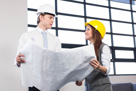 Architects looking at blueprint in office