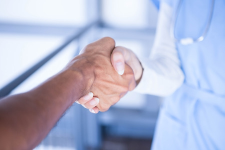 Doctors shaking hands in hospital corridorの写真素材
