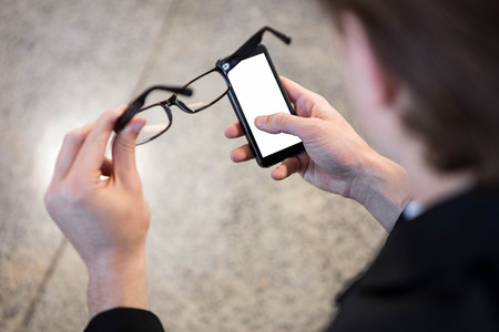 Businessman text messaging on mobile phone in officeの写真素材