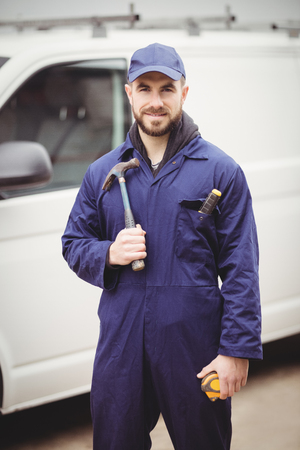 Repairman holding a hammer in front of his vanの写真素材
