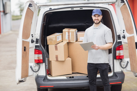 Delivery man holding clipboard in front of his van