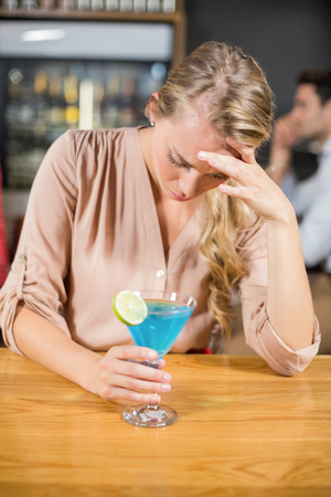 Tired woman with head in hand in a barの写真素材