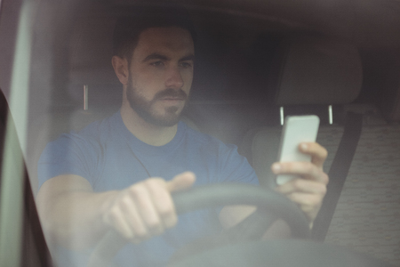 Delivery man driving his van while using smartphone