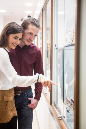 Happy couple looking at display while shopping in jeweler shopの写真素材