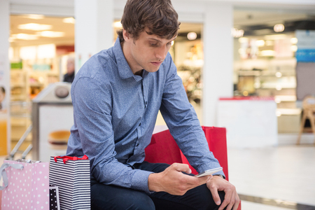 Man using mobile phone in shopping mallの写真素材