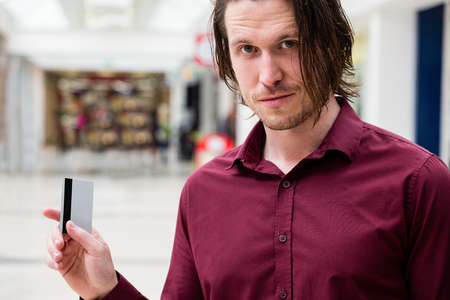 Portrait of man showing his credit card in a shopping mallの写真素材