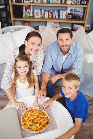 High angle portrait of family with pizza on table at homeの写真素材
