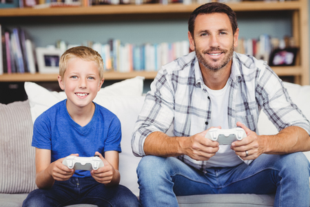 Portrait of smiling father and son playing video game at home