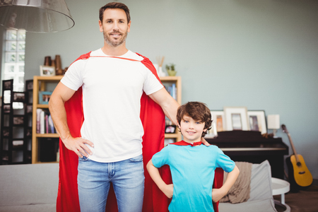 Portrait of smiling father and son in superhero costume while standing at homeの写真素材