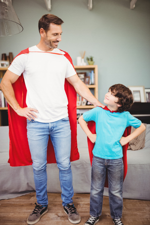 Happy father and son in superhero costume while standing at homeの写真素材