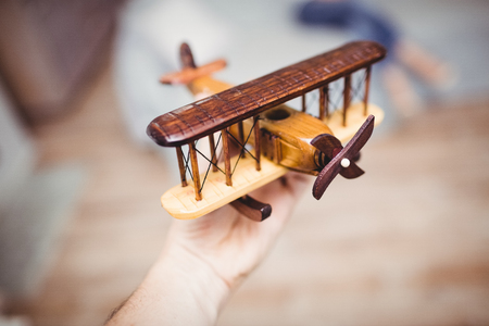 Cropped hand playing with wooden airplane at homeの写真素材