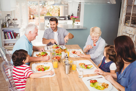 Smiling family with grandparents discussing at dining table in home