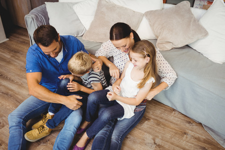 High angle view of happy family sitting by sofa in living roomの写真素材