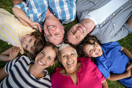 Smiling family lying in the grass in the gardenの写真素材