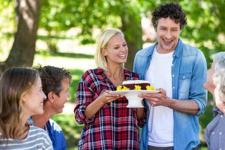 Friends having a picnic with cake in a park