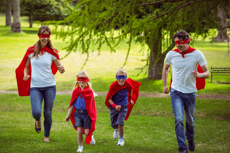 Happy family pretending to be superhero running in the parkの写真素材