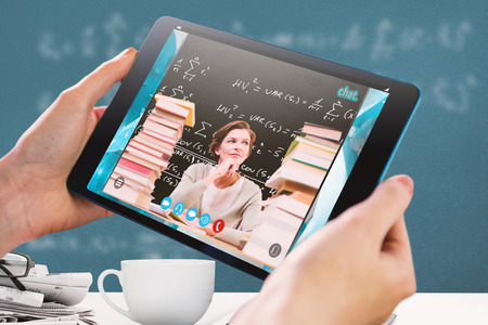 Hands holding tablet against blackboard