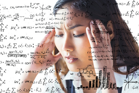 Nervous businesswoman holding her head against maths equationsの写真素材