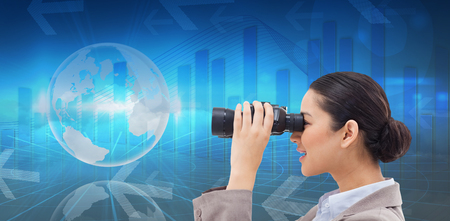 Side view of a businesswoman looking through binoculars against global business graphic in blueの写真素材