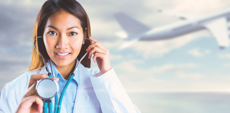 Asian doctor holding her stethoscope against bridge over water and blue skyの写真素材