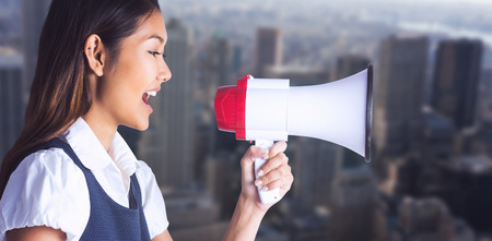 Businesswoman shooting through a megaphone against view of cityscapeの写真素材