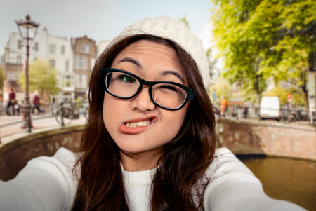 Asian woman making faces against bridge in amsterdamの写真素材