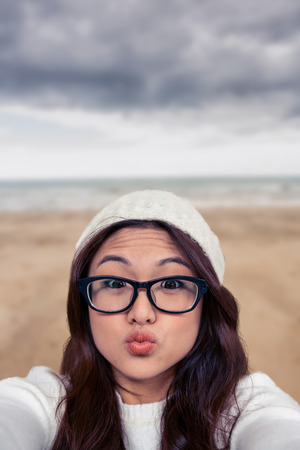 Asian woman making faces against beach sceneの写真素材