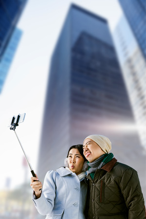 Playful couple taking selfie against building against skyscraper in cityの写真素材